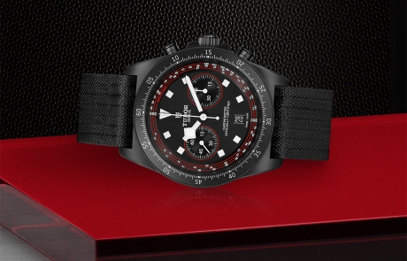 TUDOR PELAGOS FXD laid down showcasing the black, matt, red accents on the chronograph counters and tachymeter scale dial and overall elegance.